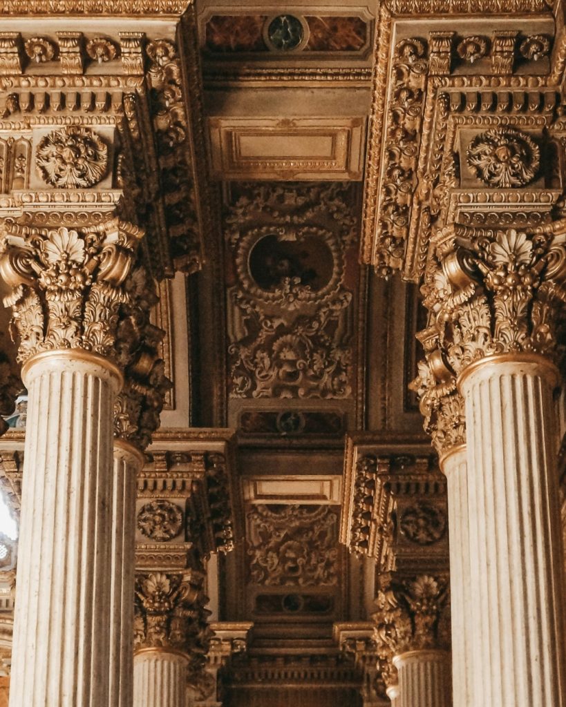 An upward perspective capturing the architectural majesty of Dolmabahçe Palace's interior. Fluted Corinthian columns with ornate gilded capitals support an intricately detailed coffered ceiling, a testament to the late Ottoman synthesis of European styles.