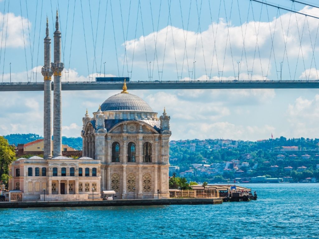 The elegant Ortaköy Mosque on the Bosphorus shore, perfectly framed by the modern 15 July Martyrs Bridge, symbolizing the beautiful blend of old and new Istanbul.
